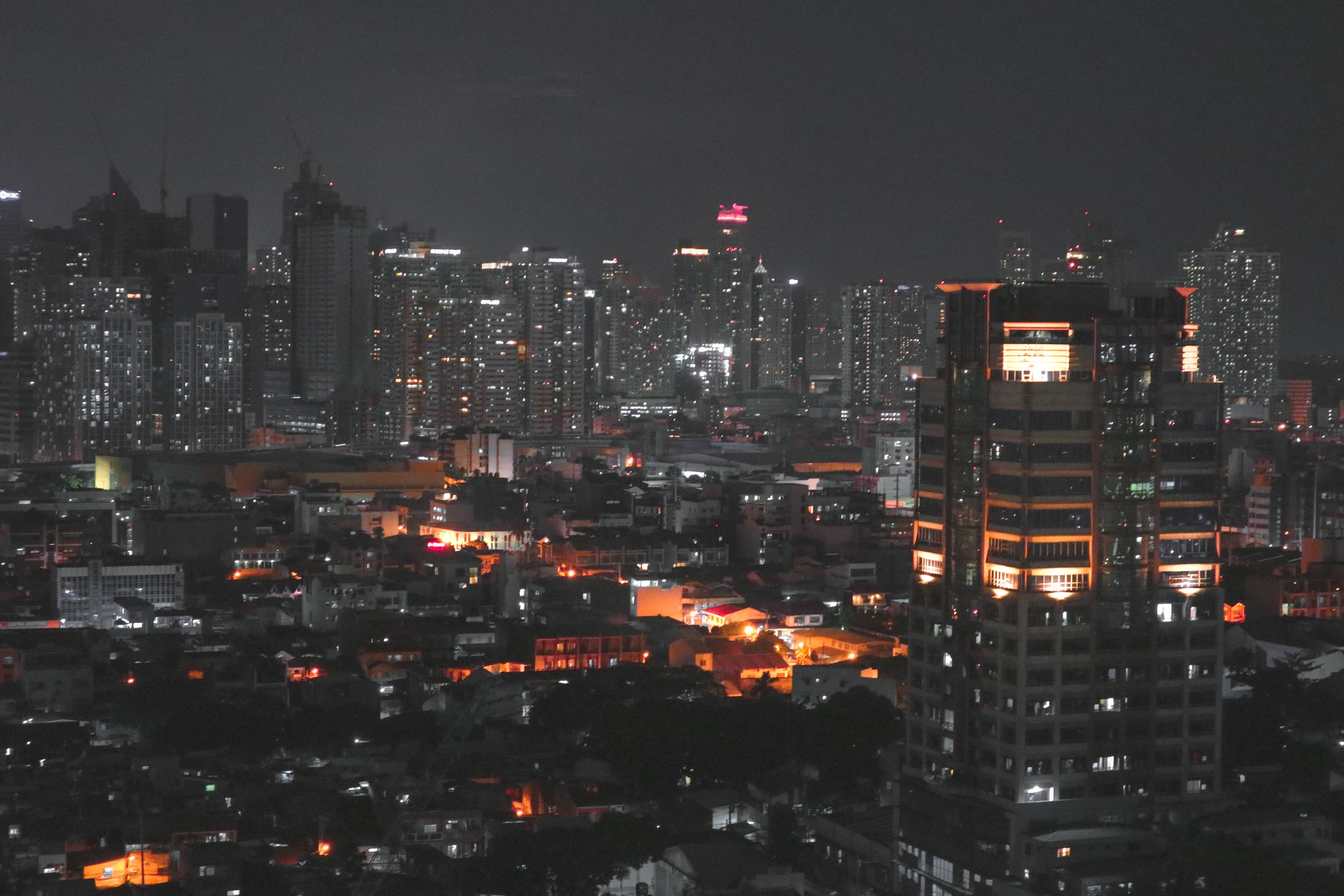 Aerial view of the Manila cityscape at night featuring brightly lit skyscrapers.