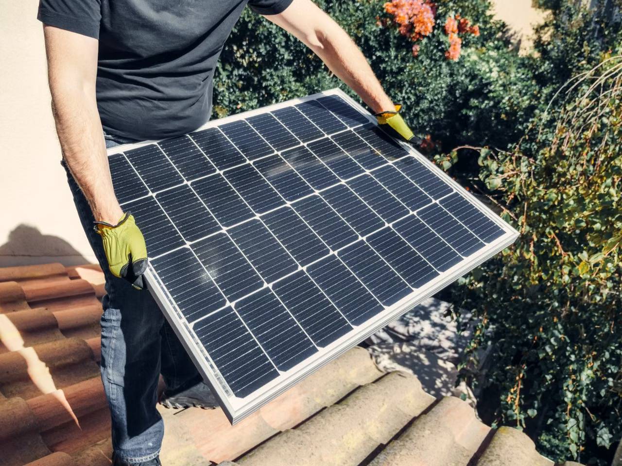 Worker installing a solar panel on a rooftop, promoting renewable energy.